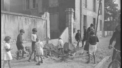 Des enfants jouent dans une rue de Nancy près d'un porche détruit.